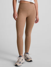 model is wearing brown high-waisted midi leggings and a white tank top.